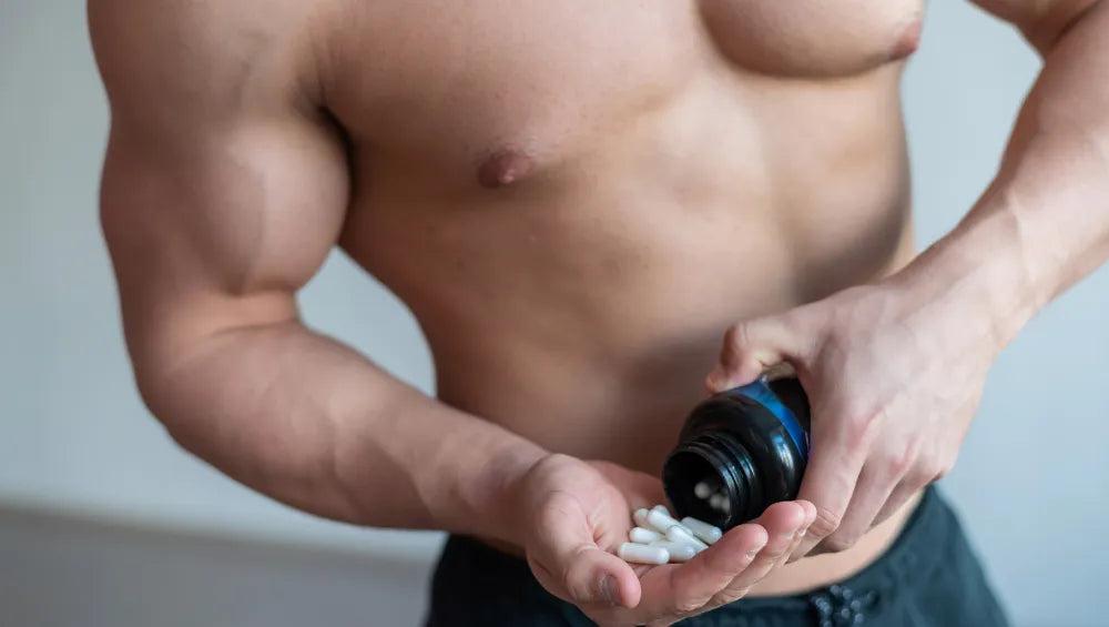 Homme torse nu musclé en train de renversé dans sa main plusieurs pilules fat burner