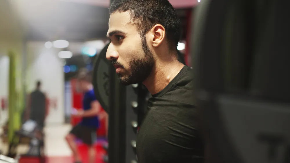 Homme en train de faire un exercice squat avec une barre olympique
