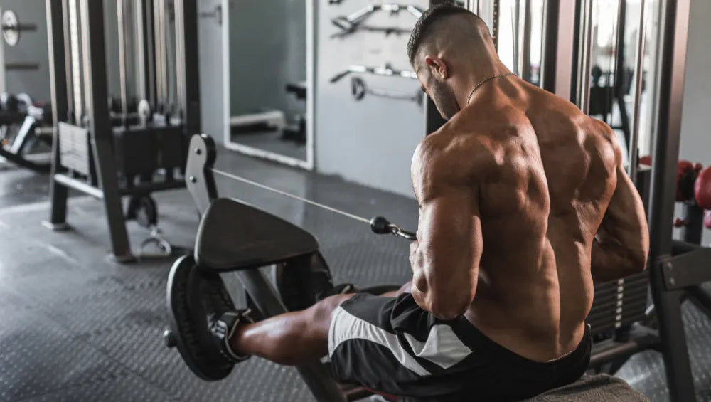 Homme sec et musclé en train de faire un tirage poulie horizontal en prise serré
