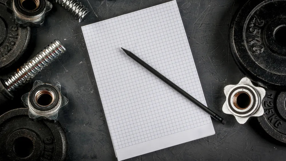 Bloc note entouré de poids et barres d'haltères