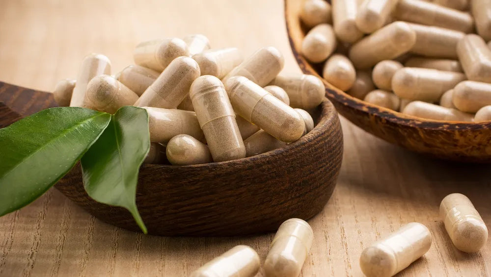 Plusieurs capsule d'ashwagandha dans 2 bol en bois