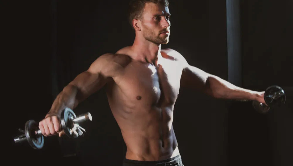 Un homme musclé torse nu en train de faire des élévations latérale aux haltères