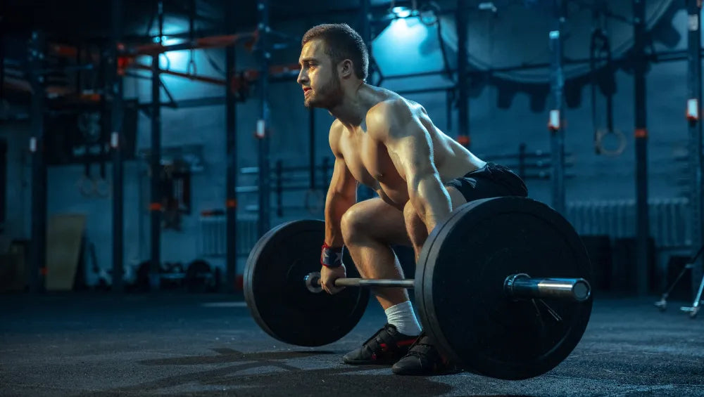 Homme torse nu en train d'executer un mouvement de soulevez de terre avec une barre olympique
