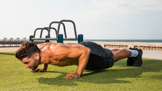 Homme musclé en train de faire une série de pompe en pleine air sur un gazon d'herbe bien vert sous un temps ensoleillé