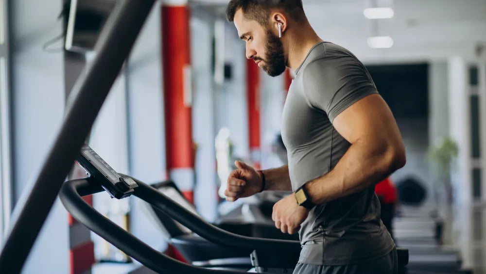 Homme qui court sur un tapis de course dans une salle de musculation à la fin de sa séance de musculation.