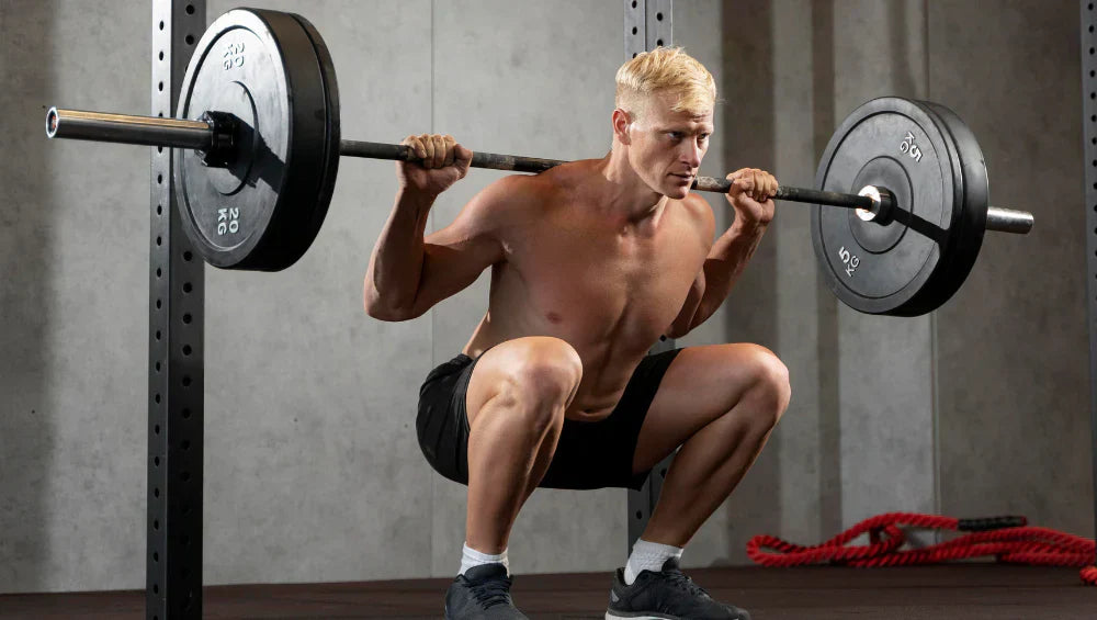 Homme qui fait un squat à la barre libre.