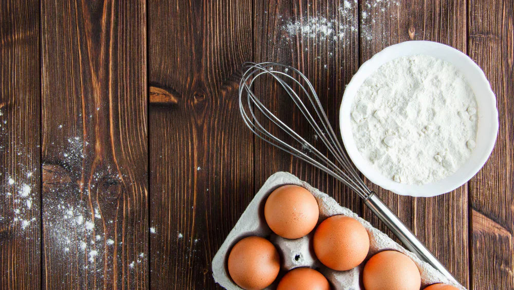 Photo d'un plan de travail de cuisine, avec des oeufs et de la farine pour une recette avec blanc d'oeuf.