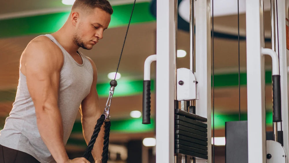Image d'un homme qui fait un exercice triceps à la poulie dans une salle de musculation.