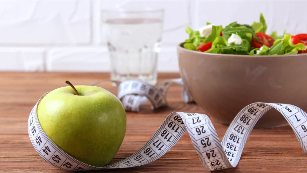 Photo d'une pomme avec un mètre ruban et une salade. 