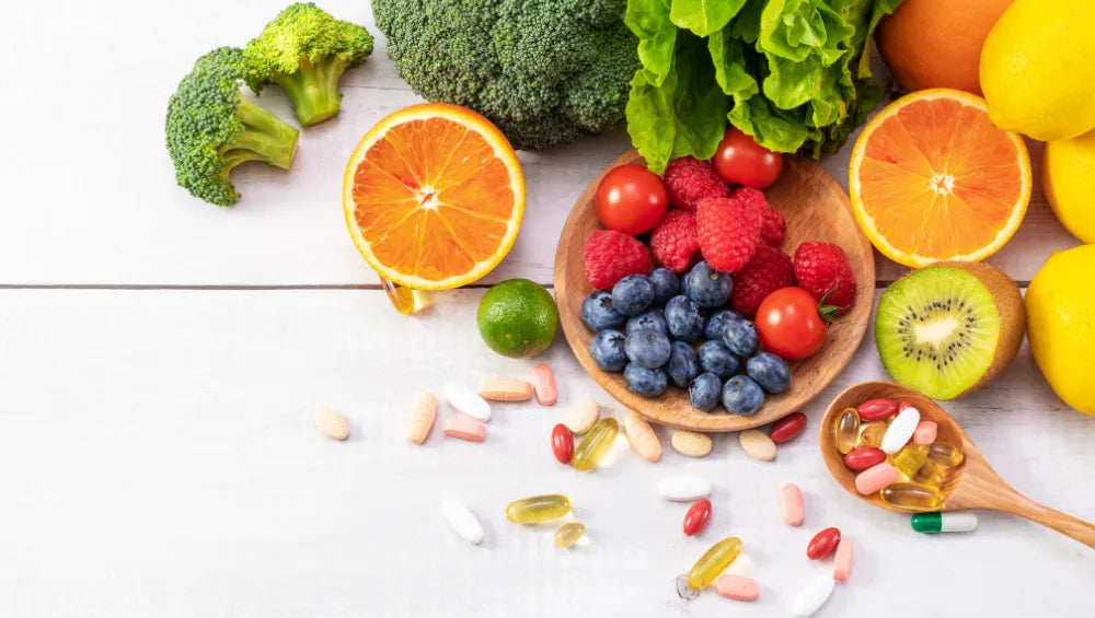 Plusieurs fruits et légumes ainsi que plusieurs pilules sur une table avec vu du haut