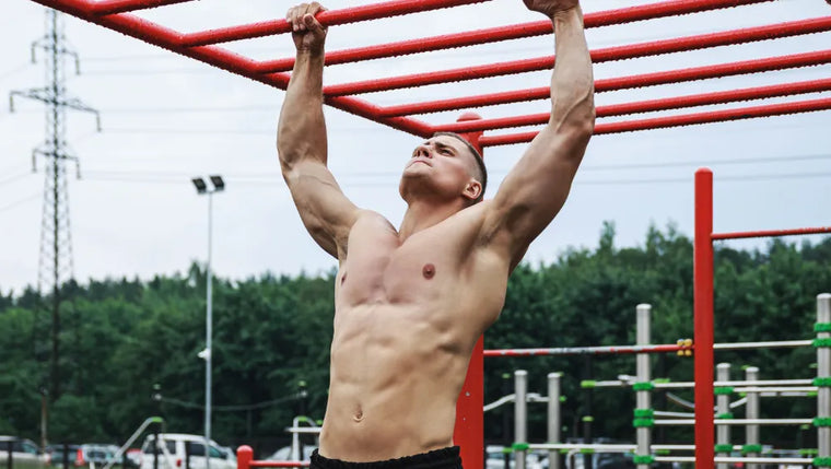 Homme musclé torse nu en train d'effectuer des tractions en pleine air