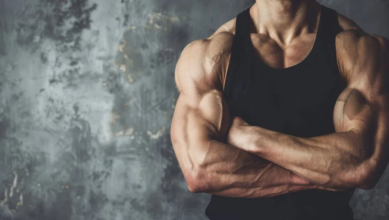 Homme musclé et sec en débardeur noir sur un fond gris avec les bras croisé