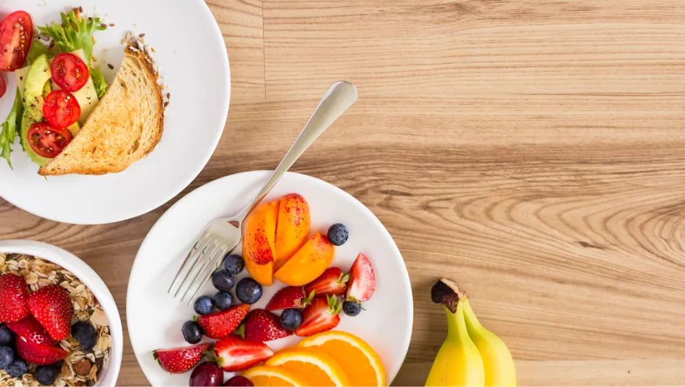 Table en bois contenant plusieurs petit déjeuner : sélection gourmande de fruits frais, de pain complet et de flocons d’avoine, idéale pour un petit déjeuner équilibré et adapté à la prise de masse.