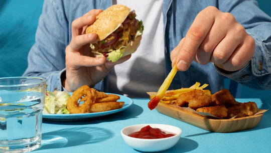 Homme qui mange un cheat meal (hamburger, frites et sauce).
