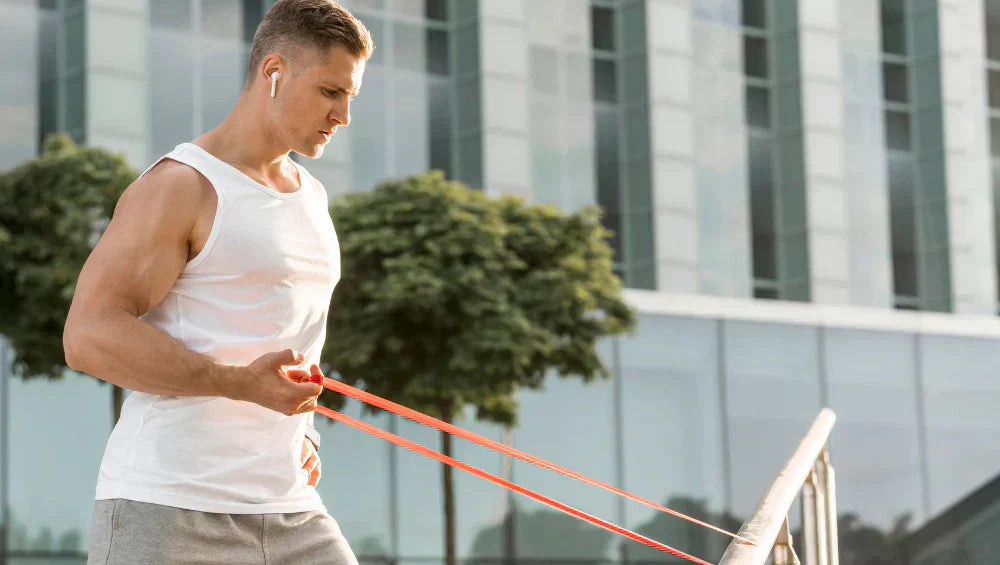 Homme qui utilise un élastique pour faire un exercice de musculation (biceps).