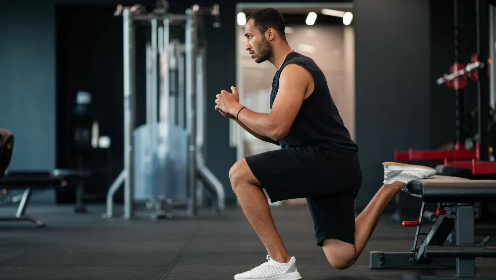Photo d'un homme qui fait une fente bulgare sur un banc de musculation.