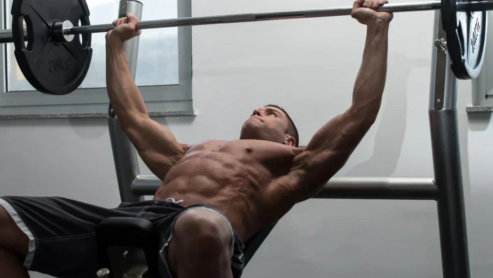 Homme qui fait un développer coucher à la barre libre pour muscler ses pectoraux.