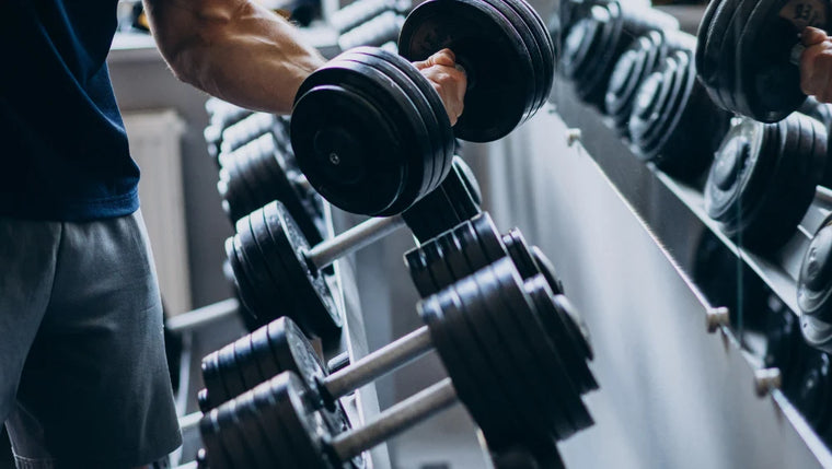 Image d'un homme qui porte un poids (haltère) dans une salle de musculation.