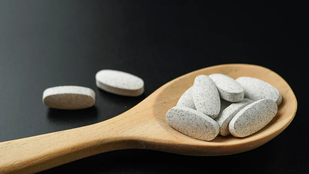 Gélules de magnésium dans une cuillère en bois. 