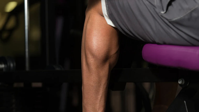 Photo d'un homme assis qui fait un exercice de musculation pour muscler ses mollets. 