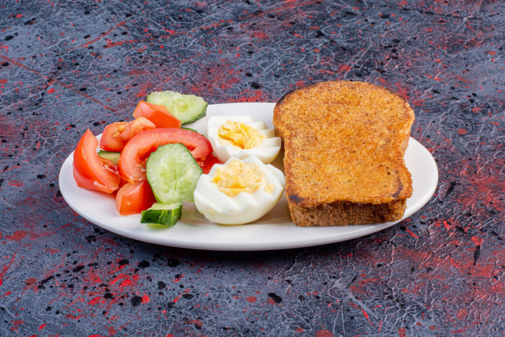 Assiette avec pain grillé, œuf et légumes crus.