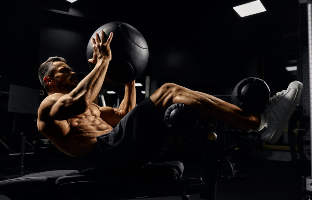 Un homme travaillant les muscles des abdos avec une balle lourde.