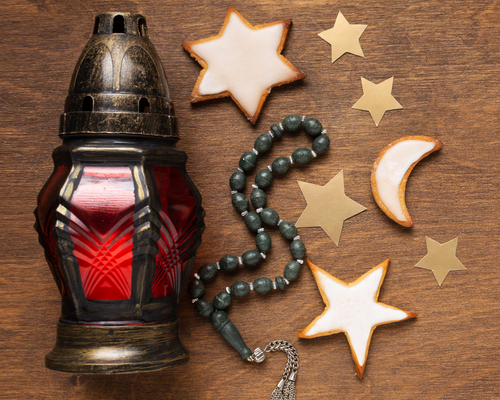 A red Arabic lamp, prayer beads, stars and a moon on a wooden table